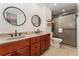 Stunning bathroom featuring dual sinks, a tile shower with a glass door, and dark wood cabinets at 938 W Peakview Cir, Littleton, CO 80120