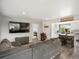 Open concept living room featuring a gray couch, TV, view to kitchen and bedroom with bright, natural light at 10536 Garrison St, Westminster, CO 80021