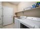 Convenient laundry room with white appliances, storage shelves, and tile flooring at 2558 Northview Pl, Castle Rock, CO 80104