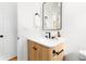 Bathroom with white walls, wood cabinet, black hardware, and a black framed mirror at 333 Quitman St, Denver, CO 80219