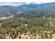 Scenic aerial view of home nestled among dense green forests with mountains in the distance at 54 Zaza Ln, Evergreen, CO 80439