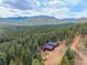 A home nestles within a lush, green landscape surrounded by mountains and trees at 54 Zaza Ln, Evergreen, CO 80439