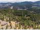A stunning aerial view showcasing the cabin nestled among the towering pines, with mountains in the background at 54 Zaza Ln, Evergreen, CO 80439