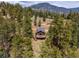 An aerial view of a cozy mountain cabin with a deck surrounded by lush trees at 54 Zaza Ln, Evergreen, CO 80439