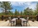 Outdoor deck area with a dining table and seating, surrounded by lush greenery at 54 Zaza Ln, Evergreen, CO 80439