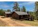 Cozy cabin featuring a chimney, wooden siding, and a wrap-around deck in a wooded setting at 54 Zaza Ln, Evergreen, CO 80439