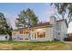Home's rear exterior boasts large windows, a stone patio, and a well-maintained lawn with mature trees at 6508 E Euclid Pl, Centennial, CO 80111