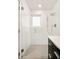 Modern all-white bathroom with glass shower, chrome fixtures, and gray tile flooring at 3435 Lawrence St, Denver, CO 80205