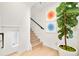 Bright staircase with hardwood steps, white walls, and colorful art, next to a fig tree at 3435 Lawrence St, Denver, CO 80205