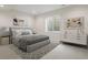 A modern bedroom is staged with art, a queen bed, area rug, and egress window at 8015 Parnassus Pl, Castle Rock, CO 80108
