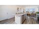 Open-concept living room with view of the kitchen, wood floors, and natural light from large windows at 22023 E 38Th Pl, Aurora, CO 80019