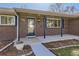 Close-up of a charming brick home featuring an inviting front porch and well-manicured landscaping at 2674 S Krameria St, Denver, CO 80222