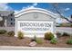 A welcoming sign that reads 'Brookhaven Condominiums' sits among green foliage and mulch in front of the complex at 1881 S Dunkirk St # 106, Aurora, CO 80017