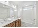 Bright bathroom with a double vanity, a large mirror, and a tub with a shower at 20724 E 57Th Ave, Aurora, CO 80019