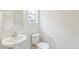 A minimalist bathroom features a pedestal sink, toilet, and a window for natural light at 20724 E 57Th Ave, Aurora, CO 80019