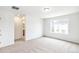 A carpeted bedroom with a view into the bathroom and a window overlooking the backyard at 20724 E 57Th Ave, Aurora, CO 80019
