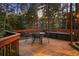 Relaxing back deck has wooden flooring, a dining table and chairs, and is surrounded by lush trees at 510 Castle Pines Dr, Castle Rock, CO 80108