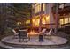 Backyard stone fire pit with seating surrounded by trees, a house with a patio, and string lights hanging overhead at 510 Castle Pines Dr, Castle Rock, CO 80108