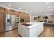 Open-concept kitchen boasts wood cabinetry, stainless steel appliances, white island with cooktop, and hardwood floors at 510 Castle Pines Dr, Castle Rock, CO 80108