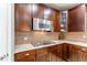 Close-up of a kitchen with dark wood cabinets, stainless steel microwave, and a gas cooktop at 6488 S Kewaunee Way, Aurora, CO 80016