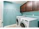 Bright laundry room with modern washer and dryer, cabinets, and a wire rack at 6488 S Kewaunee Way, Aurora, CO 80016