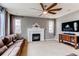 Cozy living room with a fireplace, large windows, modern fan, and sleek entertainment center at 6488 S Kewaunee Way, Aurora, CO 80016