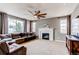 Bright living room features a fireplace, large windows, ceiling fan, and a comfortable brown sofa at 6488 S Kewaunee Way, Aurora, CO 80016