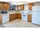 Cozy kitchen with wood cabinets, white appliances, tiled countertops, and tiled floors provides a functional cooking space at 8746 Mariposa St, Thornton, CO 80260