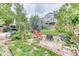 Landscaped backyard with a fire pit, red chair, mature trees, and patio for outdoor entertaining at 10191 Sagecrest St, Highlands Ranch, CO 80126