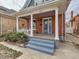 Inviting front porch with swing, supported by classic white columns and blue stairs at 3833 Umatilla St, Denver, CO 80211