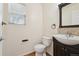 Half bath featuring dark wood vanity with mosaic backsplash, updated lighting, and hardwood floors at 16893 Trail View Cir, Parker, CO 80134
