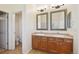 Bathroom featuring double sink vanity, two framed mirrors, neutral tile flooring, and a door to the toilet at 16893 Trail View Cir, Parker, CO 80134