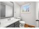 Bathroom features a grey vanity, framed mirror, toilet, and a window for natural light at 15909 E Ford Pl, Aurora, CO 80017