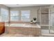 Bright bathroom featuring a tiled tub, a glass shower, and natural light from two windows at 10646 Amesbury Way, Highlands Ranch, CO 80126