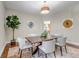 Inviting dining area with natural light, wooden table with white seating, hardwood floors and decorative plant at 10646 Amesbury Way, Highlands Ranch, CO 80126