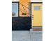 Close-up of the front entrance showing a yellow door, wood facade, and brick accent at 5261 Chandler Way, Denver, CO 80239