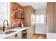 Modern kitchen with light wood cabinets, exposed brick, and floating shelves at 2809 Forest St, Denver, CO 80207