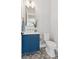 Stylish powder room featuring a blue vanity, decorative mirror, modern fixtures, and patterned tile floor at 1425 Burt Ave, Berthoud, CO 80513