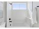 Bright white bathroom features a shower over tub with modern fixtures and a window at 1425 Burt Ave, Berthoud, CO 80513