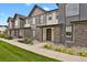 Modern townhome exterior showcasing stone accents, neutral siding, covered entry, and landscaped front yard for curb appeal at 19733 W 93Rd Ln # D, Arvada, CO 80007