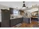 Modern kitchen features dark cabinetry, granite countertops, wood floors, and view into the dining area at 18496 Keyser Creek Ave, Parker, CO 80134