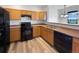Functional kitchen with wood cabinets, black appliances, and wood-look flooring at 12713 Leyden St # E, Thornton, CO 80602