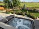Inviting hot tub overlooking an expansive green space with a wooden fence, mature trees, and colorful flowerbeds at 800 Meadowlark Dr, Erie, CO 80516