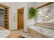 Bathroom showcasing a tub, a large window, and an adjacent closet for storage at 11220 S Deer Creek Rd, Littleton, CO 80127