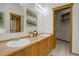 Bathroom featuring double vanity sinks, bright lighting, warm cabinets, and a decorative mirror at 11220 S Deer Creek Rd, Littleton, CO 80127