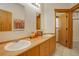 Well-lit bathroom featuring double sinks, light wood cabinets, and tile flooring at 11220 S Deer Creek Rd, Littleton, CO 80127