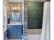 Charming bathroom with unique wallpaper, blue vanity, and tiled shower at 3330 E Tennessee Ave, Denver, CO 80209