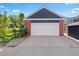 Detached two-car garage with white doors and stylish brick and navy siding at 3330 E Tennessee Ave, Denver, CO 80209