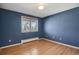 A simple bedroom has hardwood floors, a window, and blue textured walls at 5460 S Locust St, Greenwood Village, CO 80111