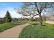 Scenic view of a community park with walking path, benches, mature tree, and lush green grass at 11785 W Belleview, Littleton, CO 80127